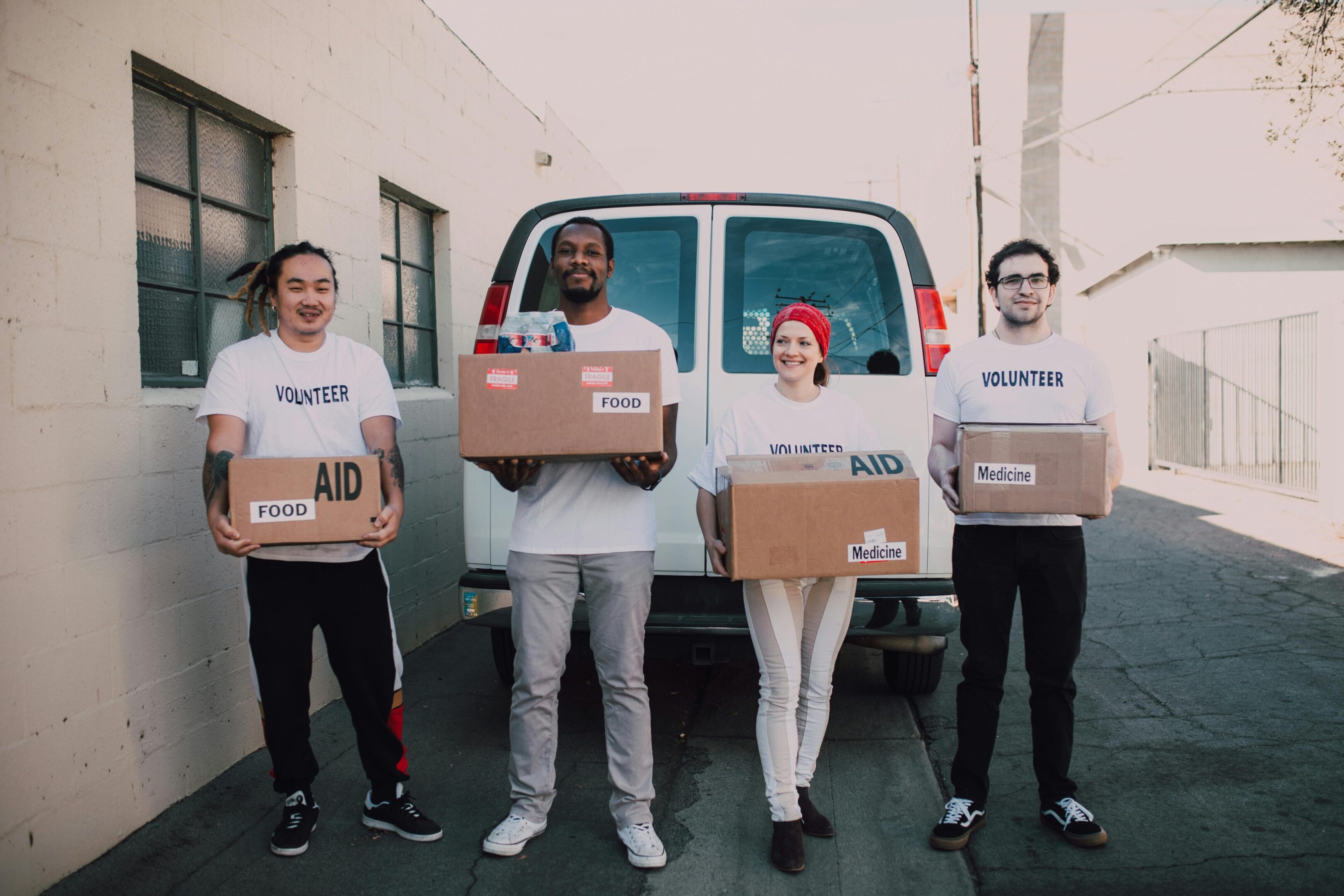PHOTO #7 Four people holding boxes in front of a van.