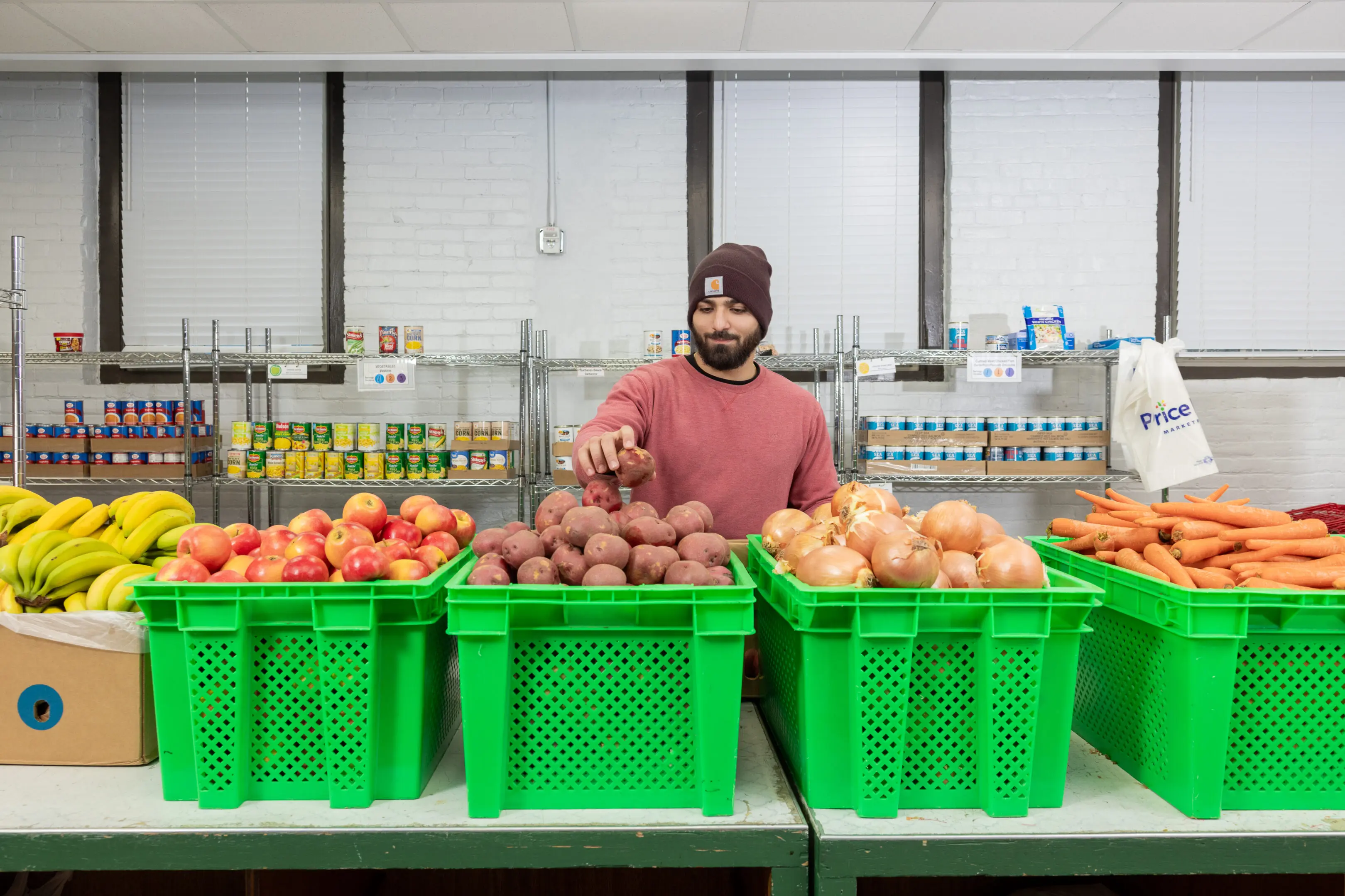 03-24 Allentown Area Ecumenical Food Bank-38 A man standing in front of three green baskets filled with fruit.