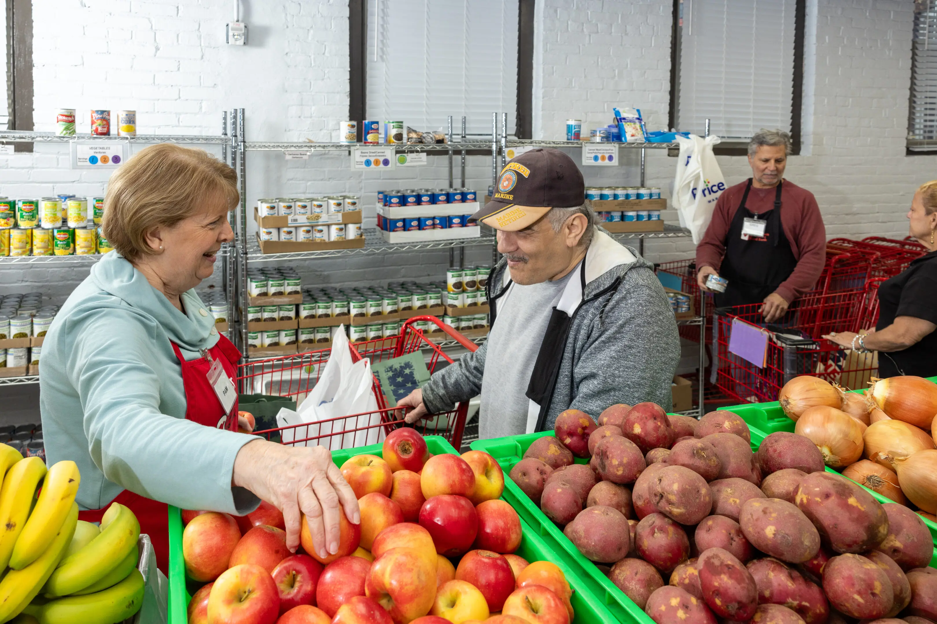 What we do - HERO A man and woman shopping for apples at the grocery store.